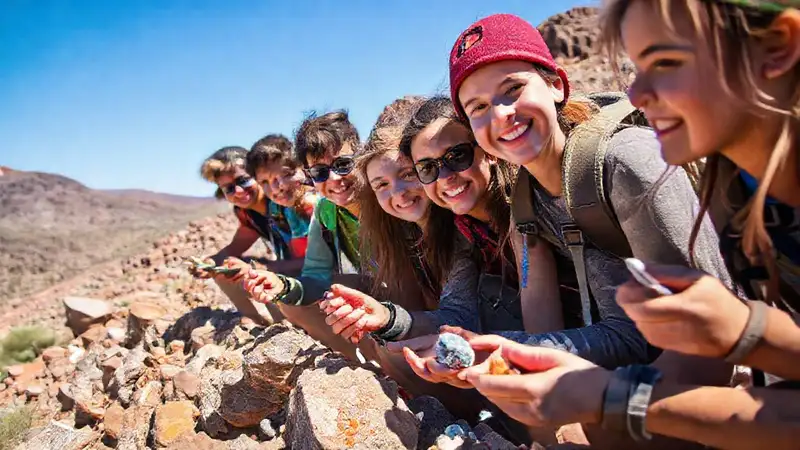 Estudiantes explorando rocas con entusiasmo y herramientas