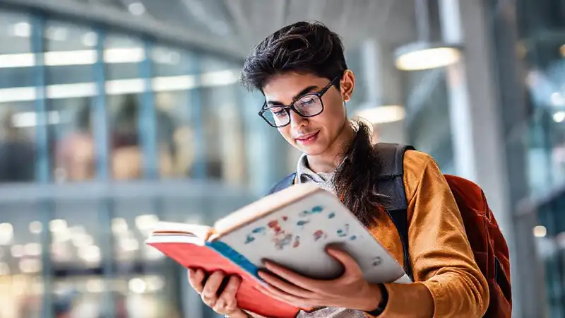 Estudiante aspirante en campus con libros farmacéuticos