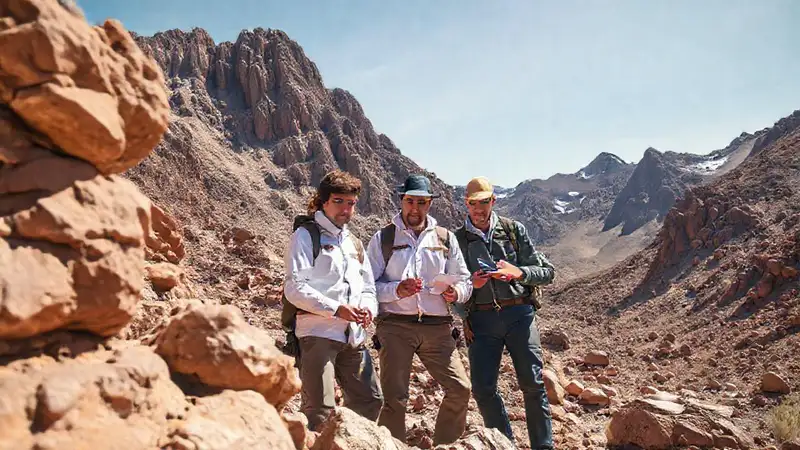 Geólogos colaborando en montaña, muestra liderazgo