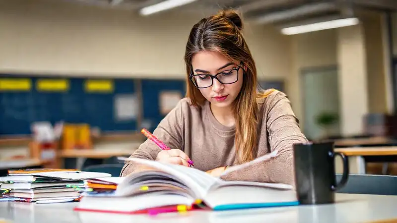 Estudiante concentrado con libros y notas coloridas