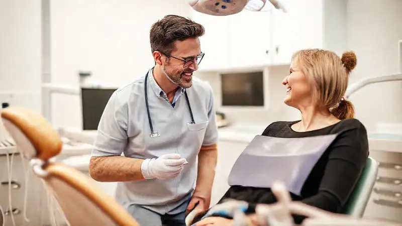 Dentista y paciente conversando en clínica moderna