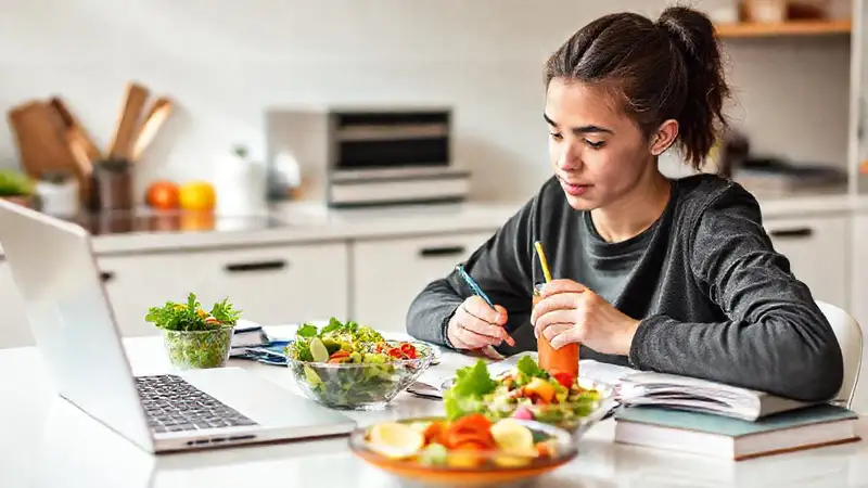 Estudiante estudiando con comida saludable y energía